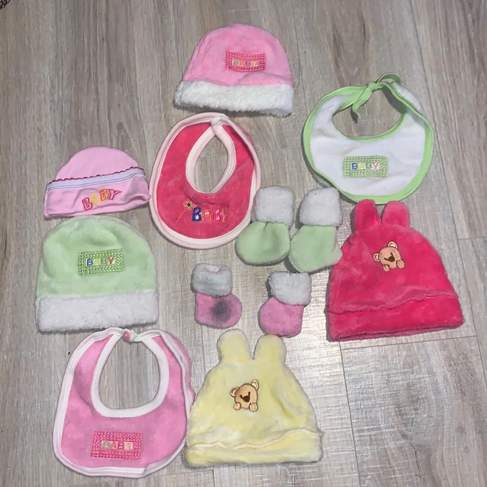 Colorful bundle of plush baby bibs, hats, and mittens